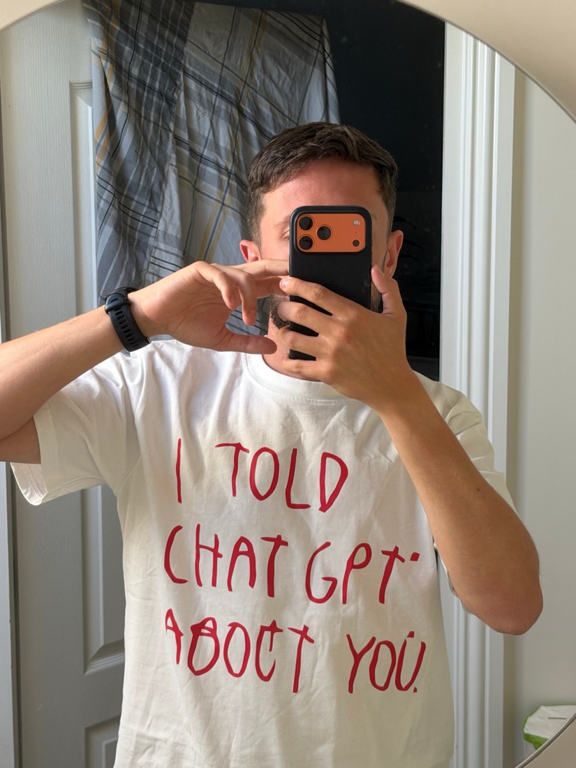 Mirror selfie of Morgan in a white T-shirt that says I told ChatGPT about you